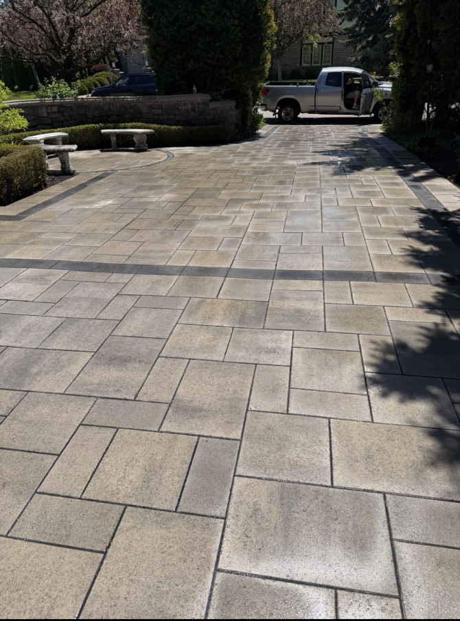 Large interlocking paver driveway with a geometric layout and landscaping