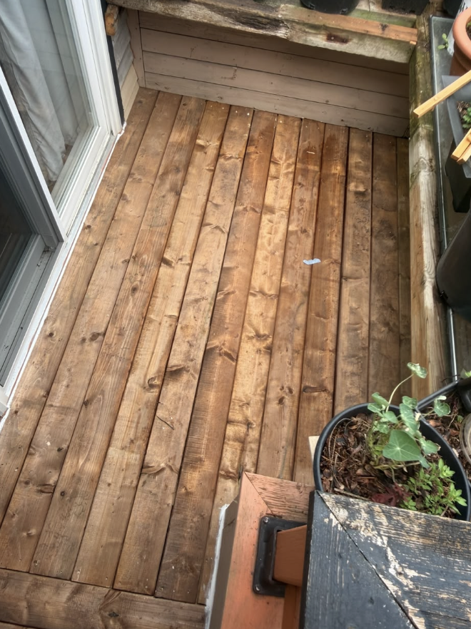 Completed wooden deck with warm brown boards beside a home