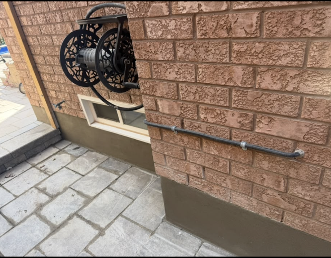 Brick exterior wall with fresh parging and stone paving below